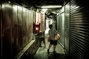 Woman in alleyway looks at shutter in Bangkok Thailand