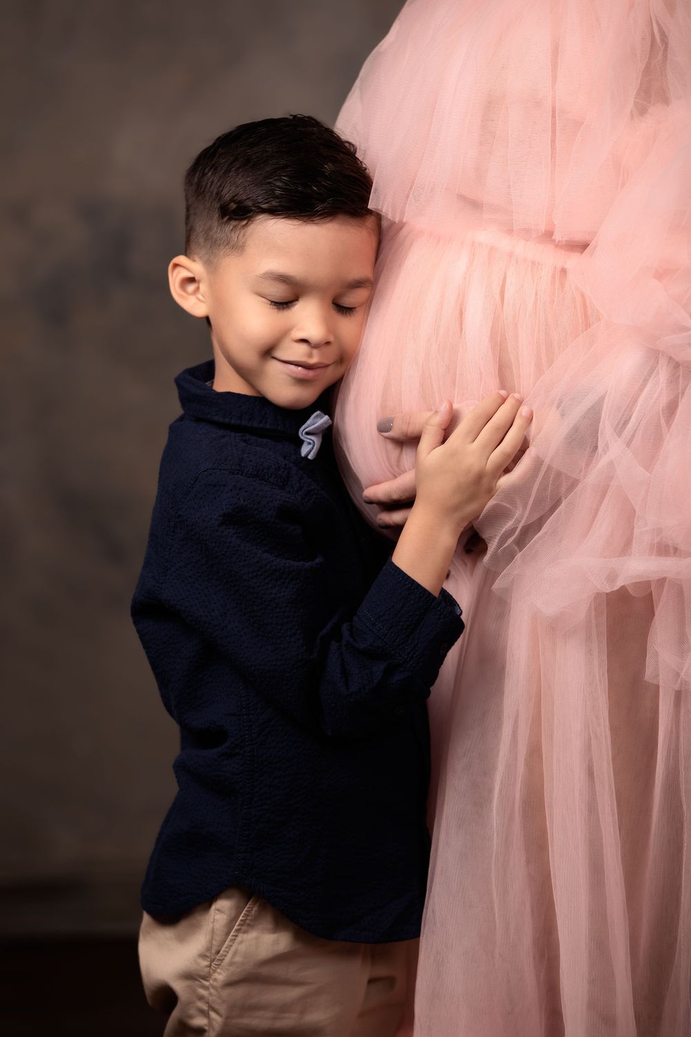 Portrait of a child hugging his mother's pregnant belly.