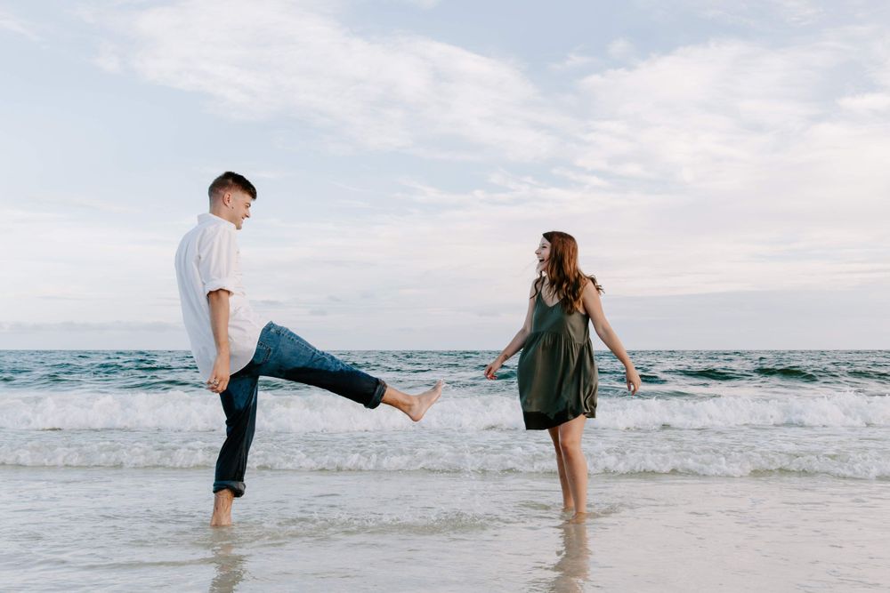 man kicking water at woman on the beach in Destin, Florida