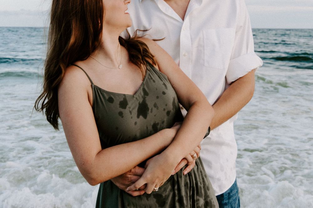 couple with their arms wrapped around each other on the beach