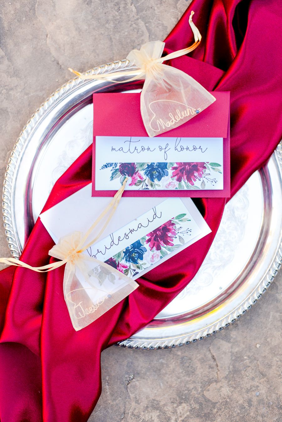 bridesmaids cards and wine rings on a dark red fabric
