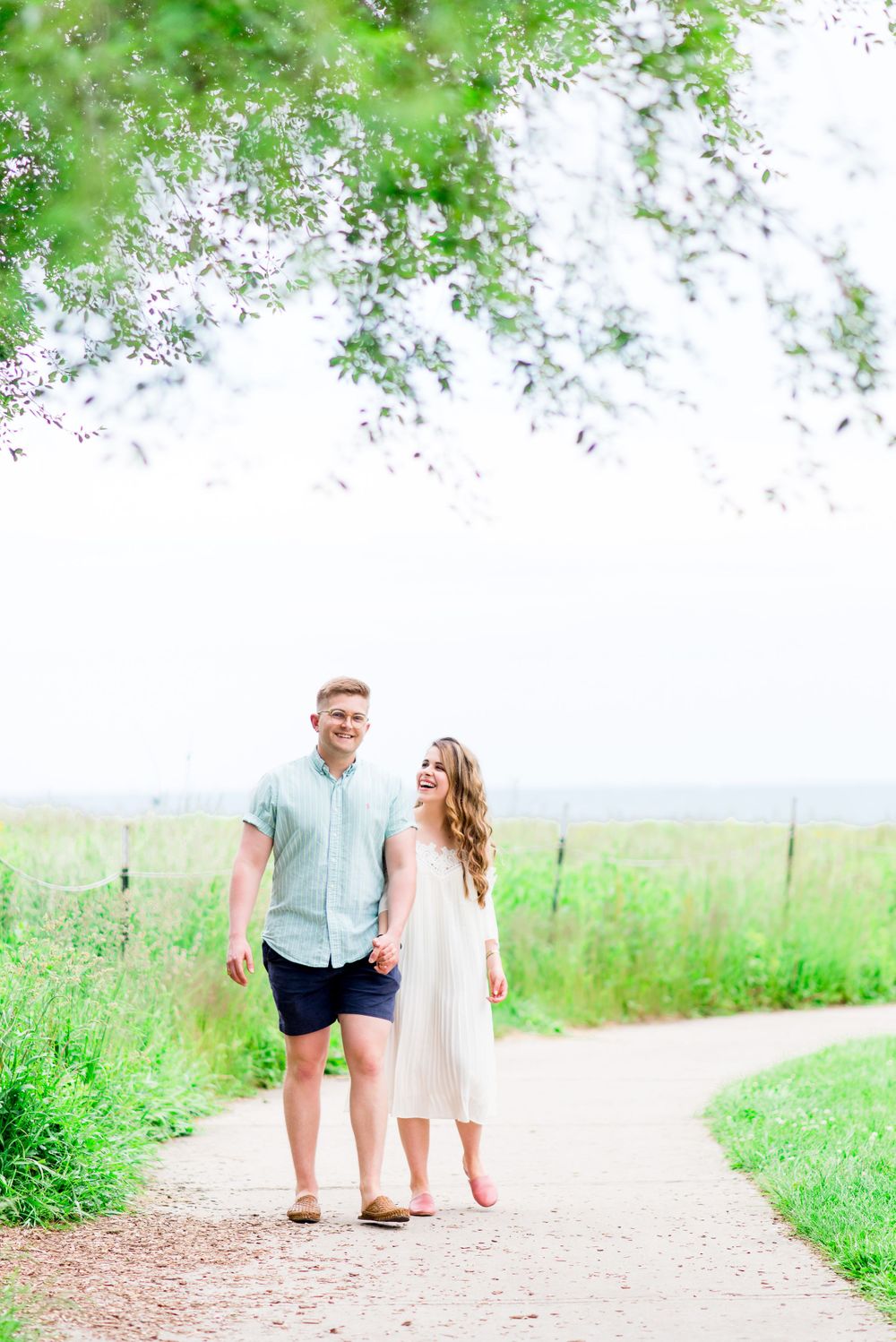 young engaged couple in blue and white laughing on Montrose Harbor trail for Chicago sunrise engagement pictures