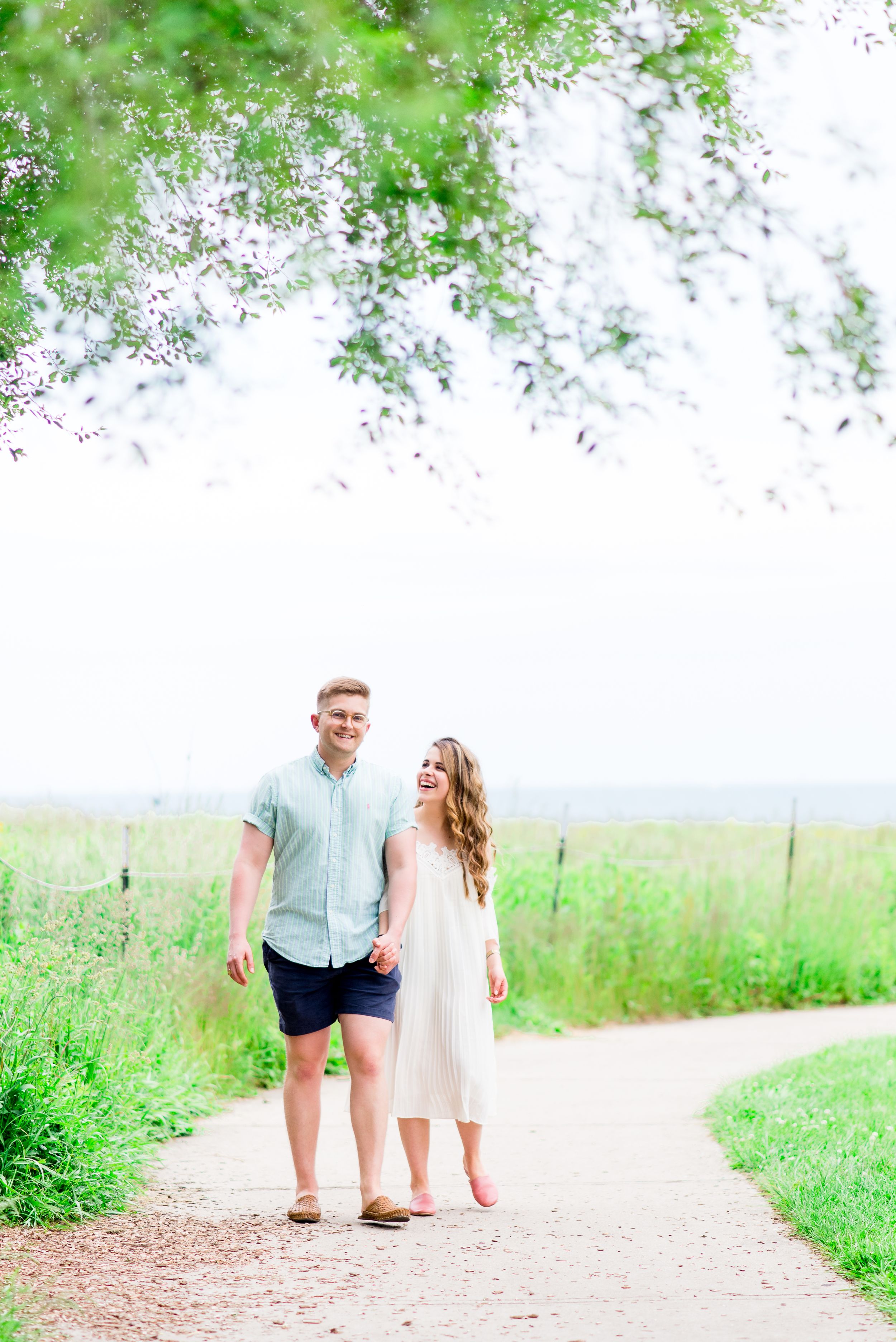 young engaged couple in blue and white laughing on Montrose Harbor trail for Chicago sunrise engagement pictures
