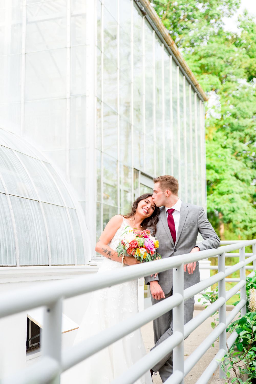 groom kissing bride on forehead at their Krohn Conservatory Wedding while bride smiles