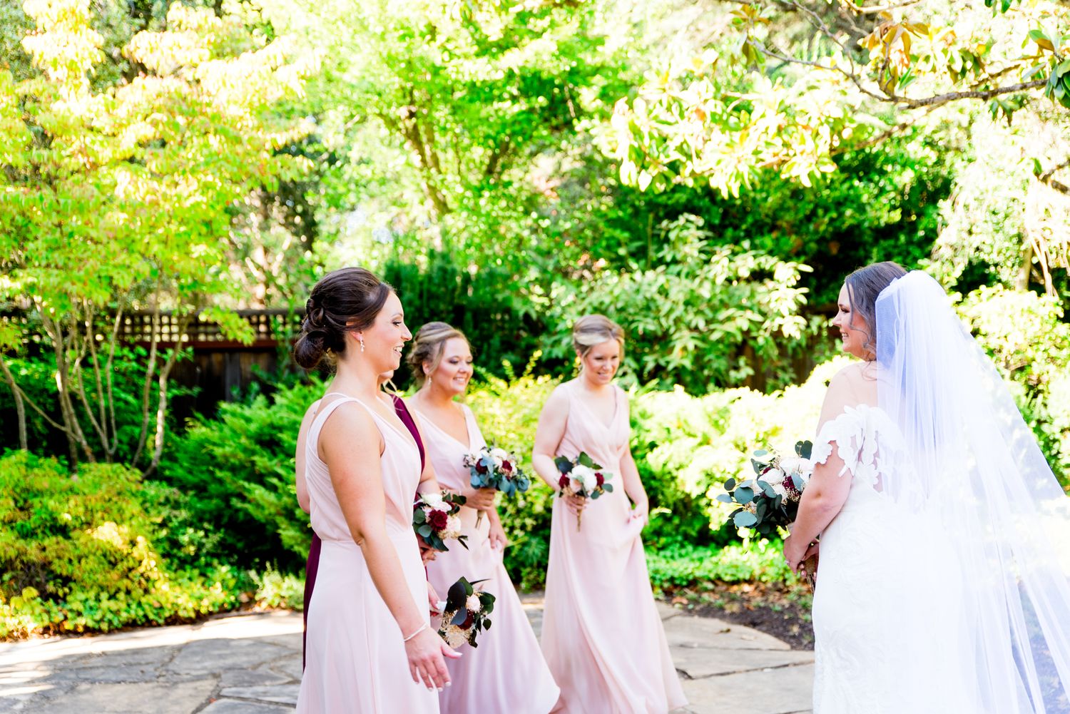 A bride having a first look with her bridesmaids in the AirBNB courtyard in Northern California