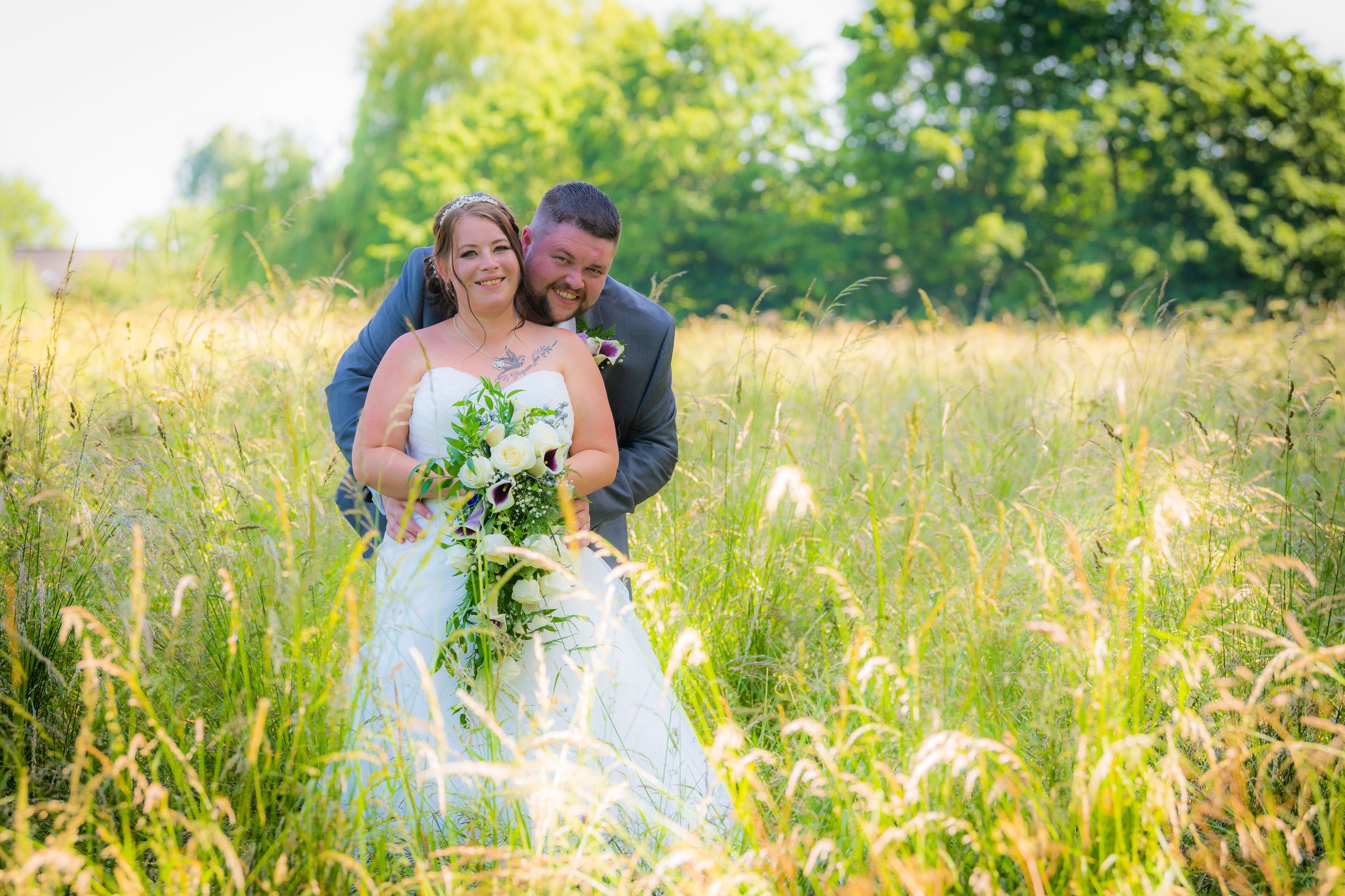 large groom behind his bride in then fields