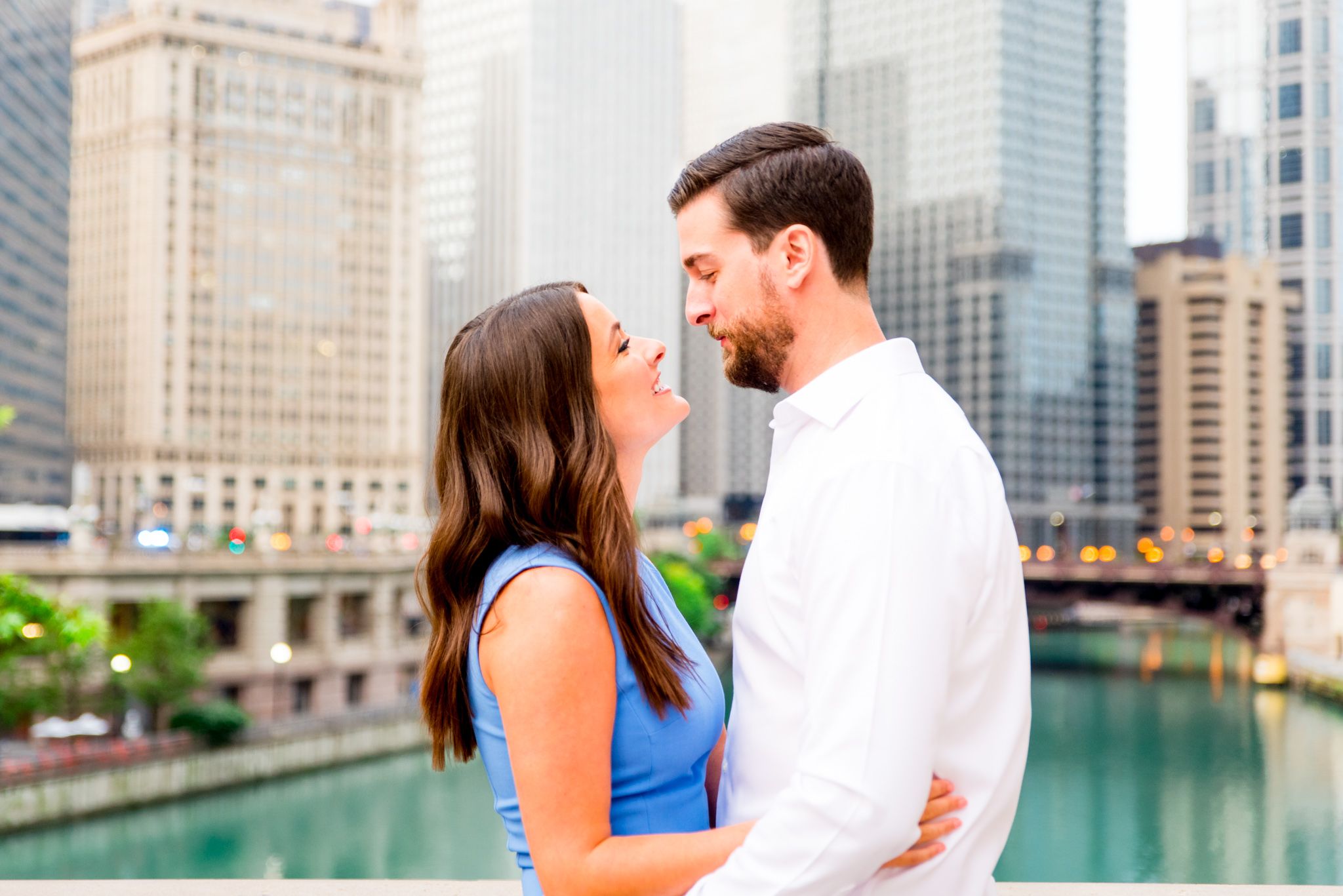 young engaged man and woman looking at each other in front of Chicago River near the Wrigley building at sunrise