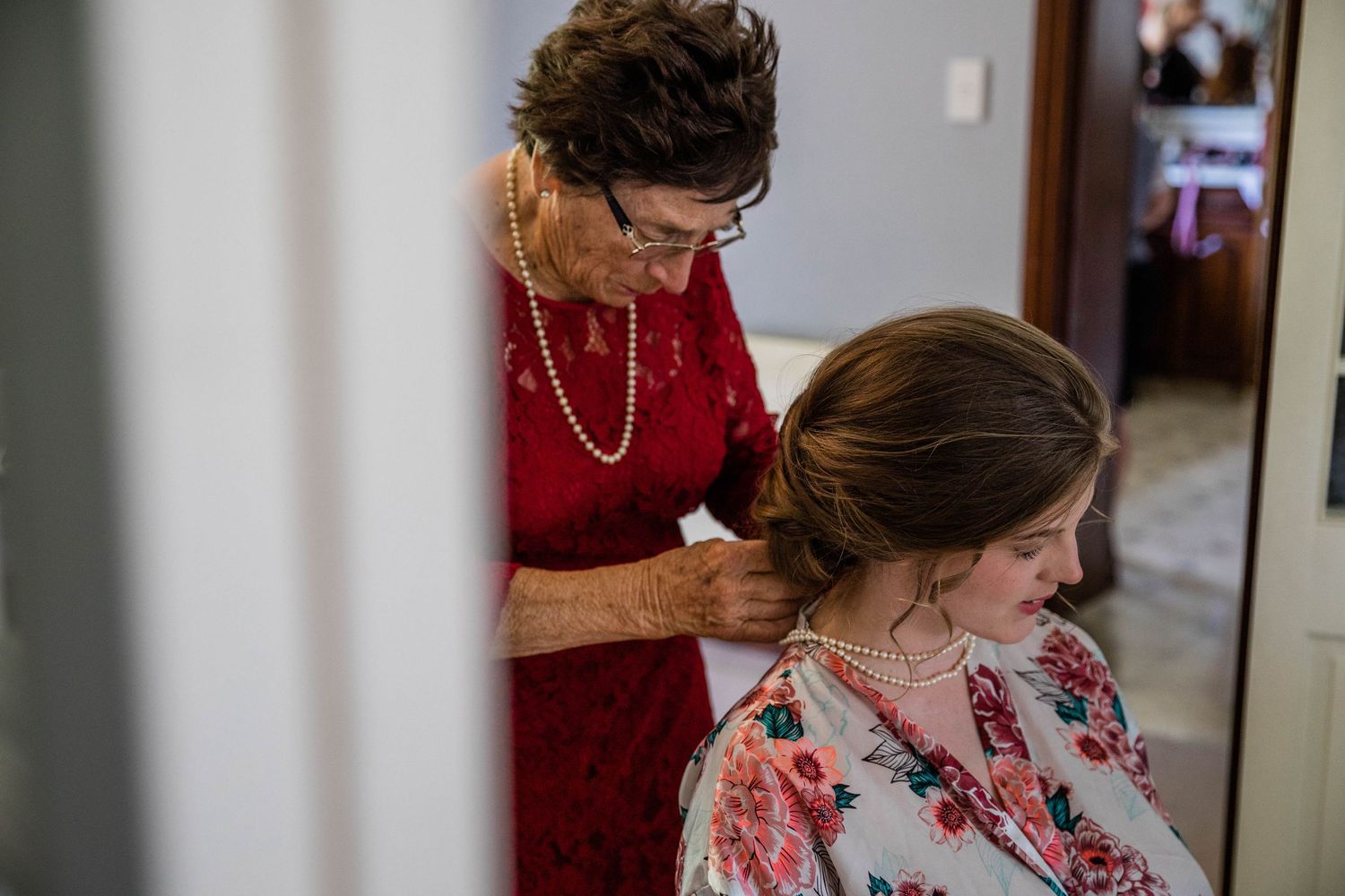Grandma putting pearls on Bride