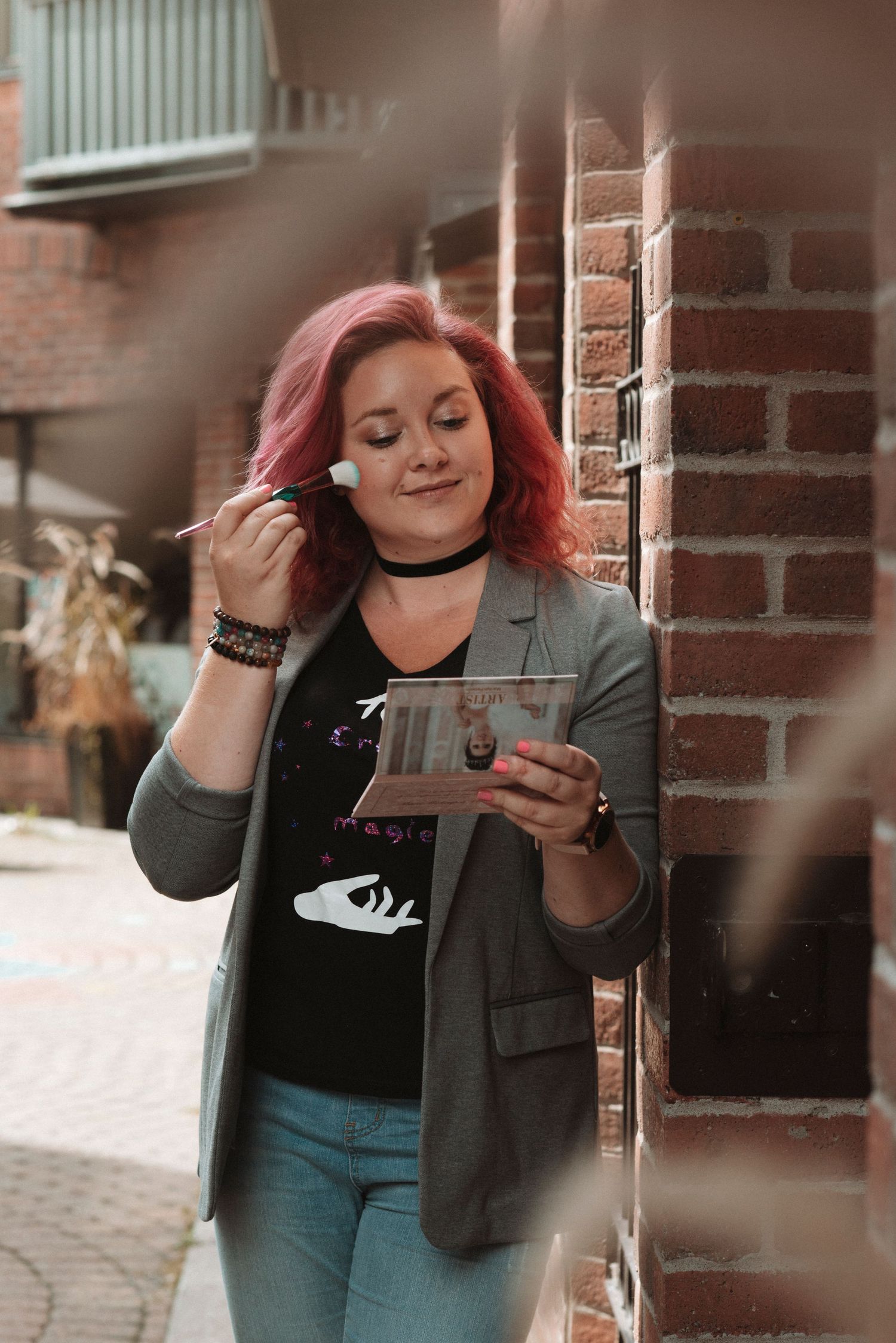 Woman with bright red hair enjoying takeout food against a brick wall exterior.