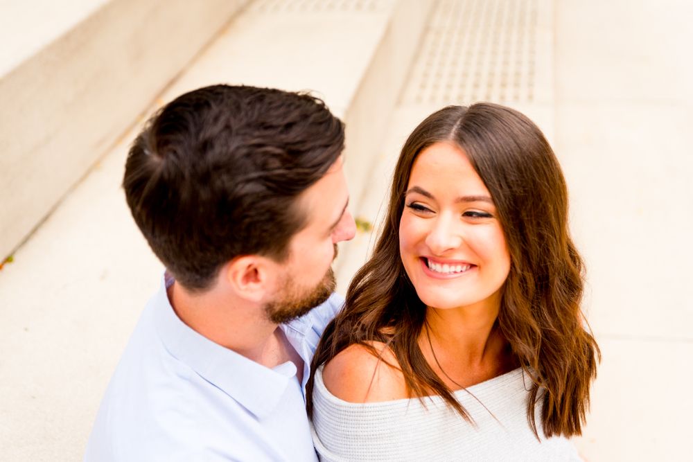 woman with brown hair looking at fiance and smiling on steps at Chicago Riverwalk engagement pictures