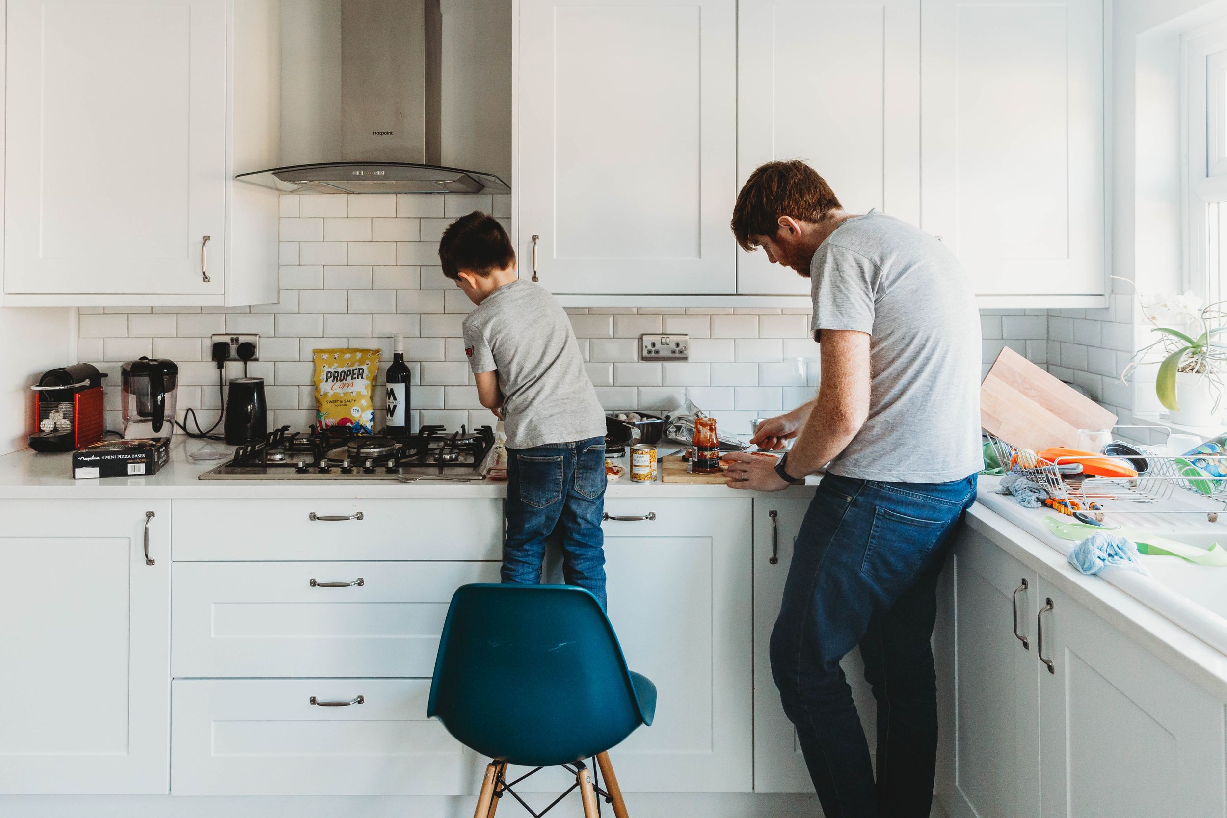 son and dad in grey t-shirts and jeans standing in kitchen