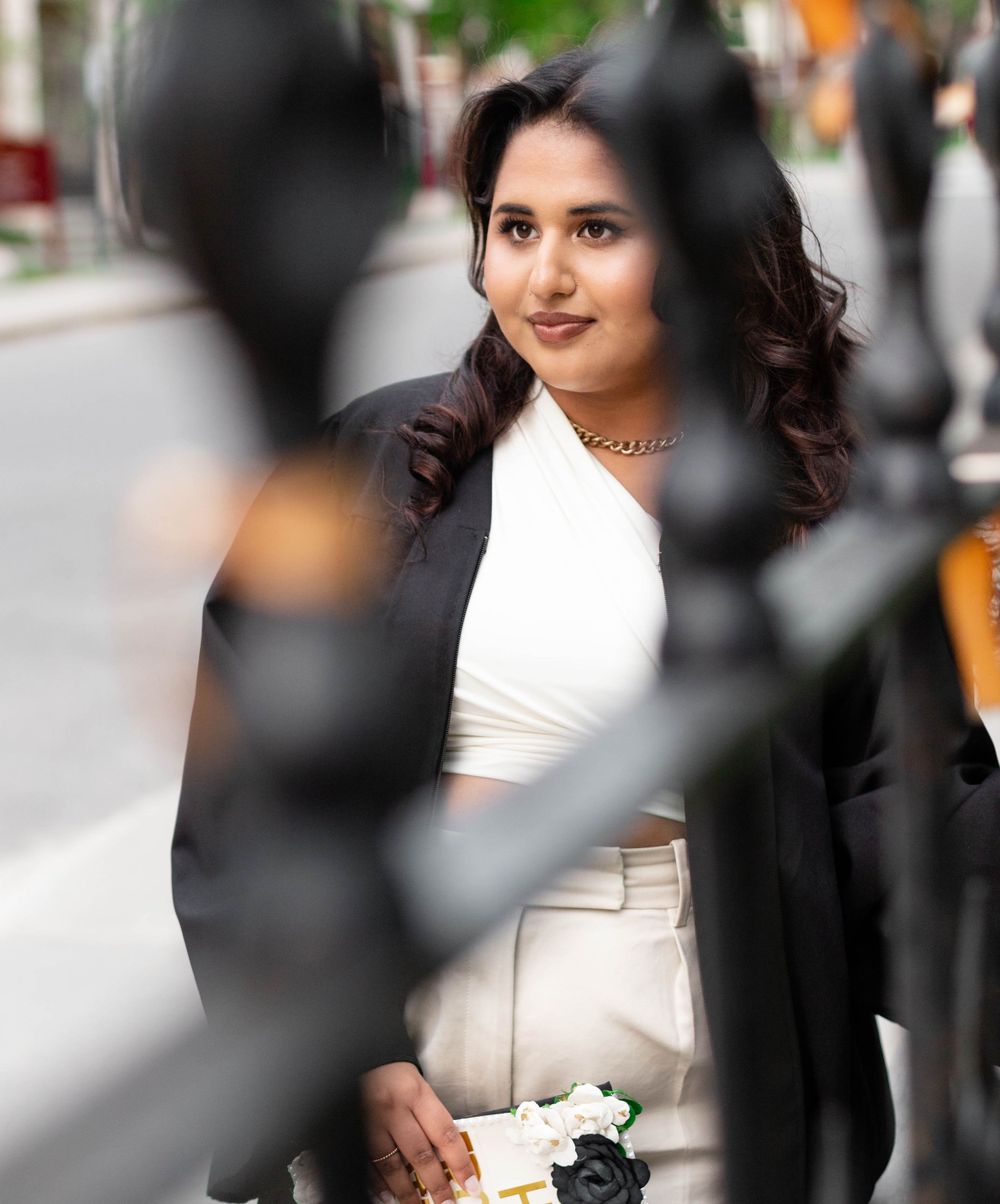 Portrait through decorative railings showing woman in white top and elegant attire.