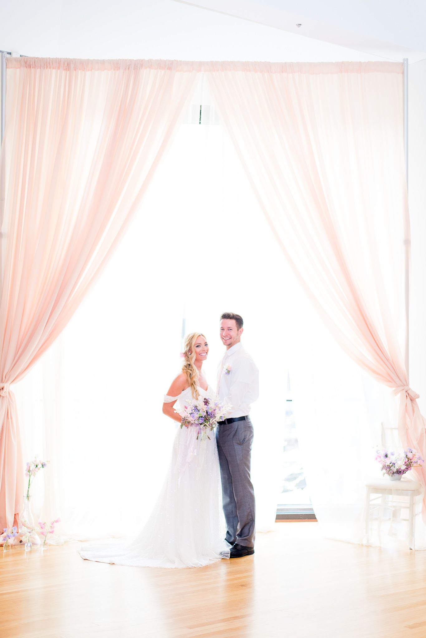 bride and groom smiling in front of pale pink curtains and window at The Center Cincinnati