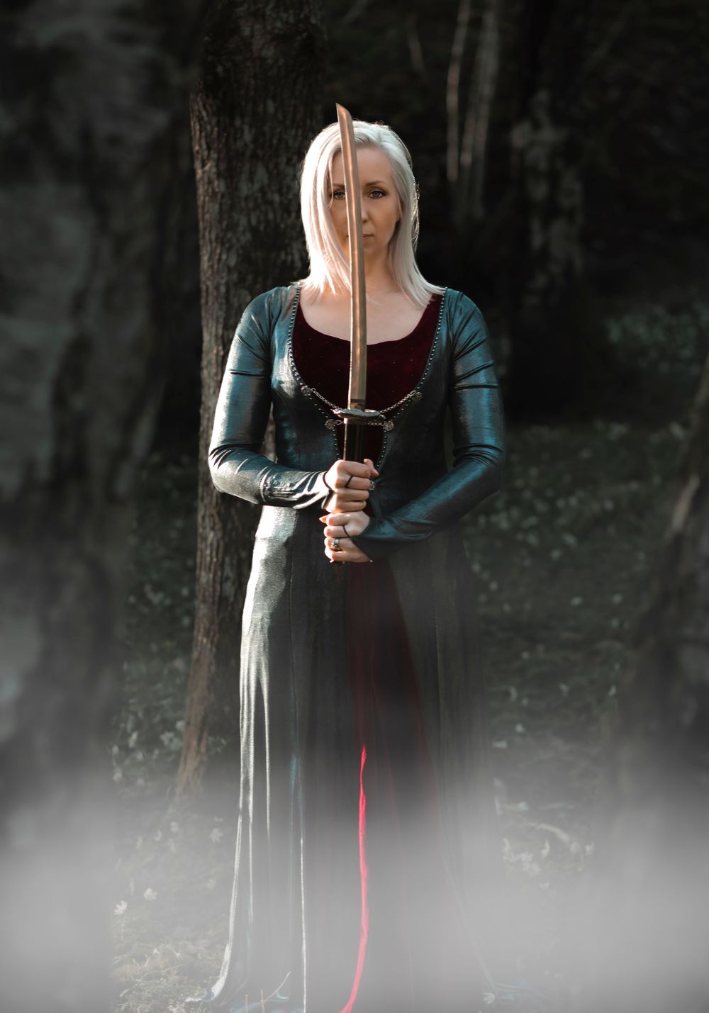 Medieval-style warrior holding sword in misty forest setting.