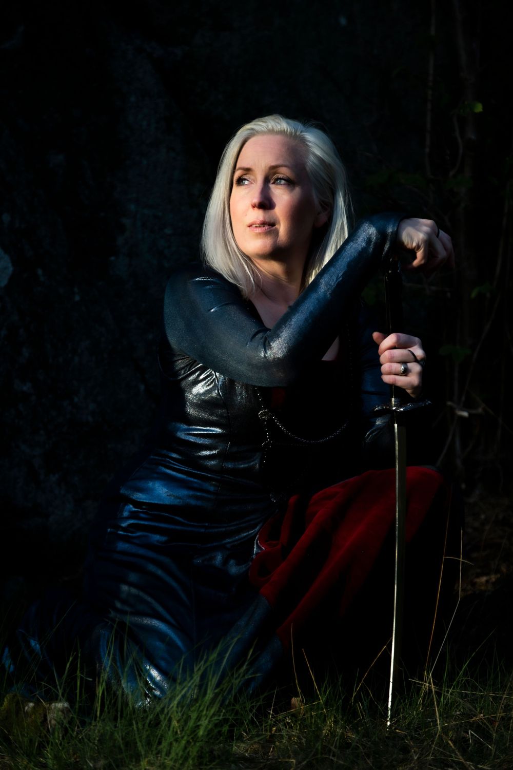 Dramatic portrait of warrior with sword against dark background.