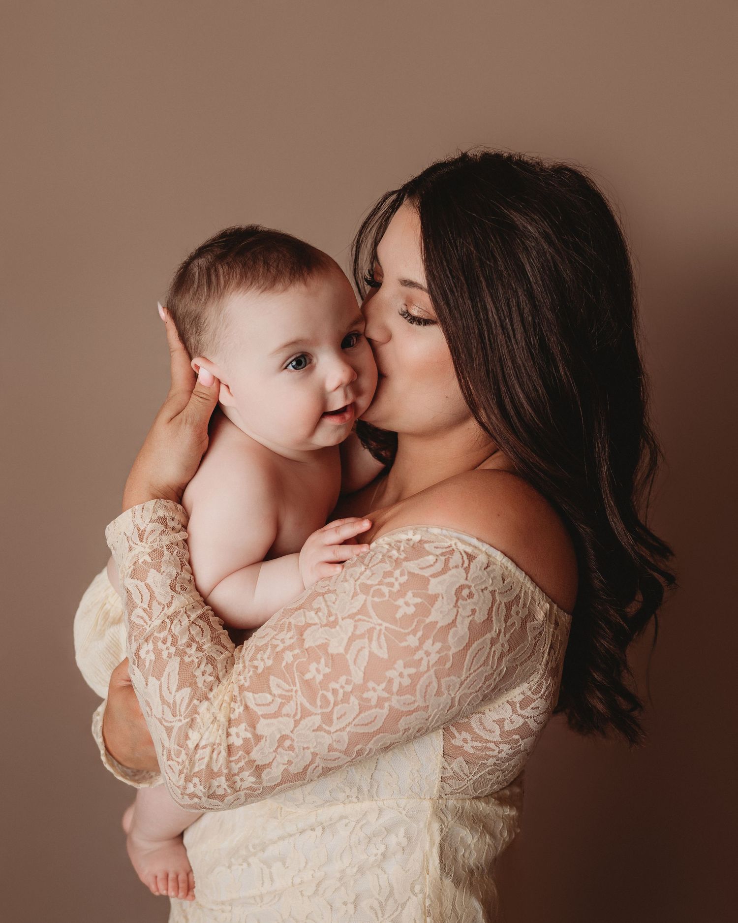 mom and baby boy poising cream lace dress mom kissing baby cheek studio session