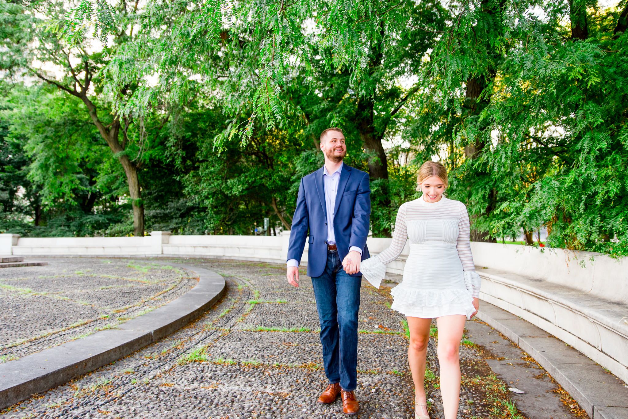 young engaged couple in white and navy walks through Millennium Park