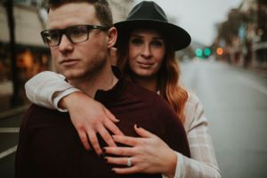 redhead looking at the camera in a hat while wrapping arms around man