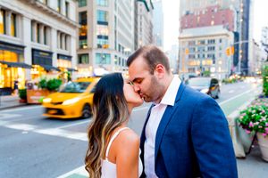 young engaged man and woman kissing in front of yellow taxis in downtown Manhattan at sunset engagement photos