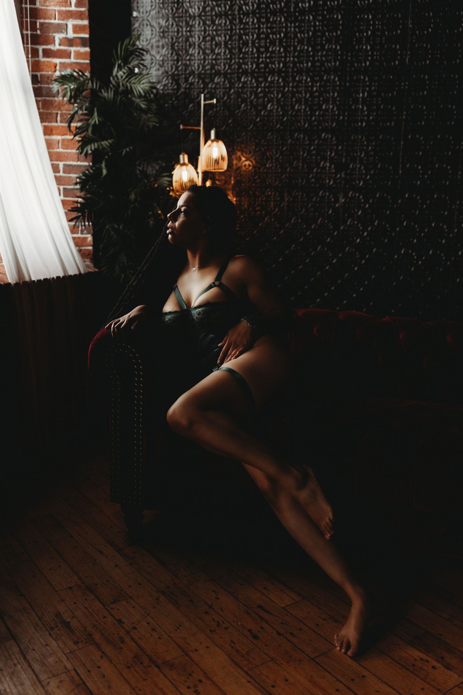 A silhouetted figure in graceful dance pose against exposed brick wall and warm lighting from vintage sconces.