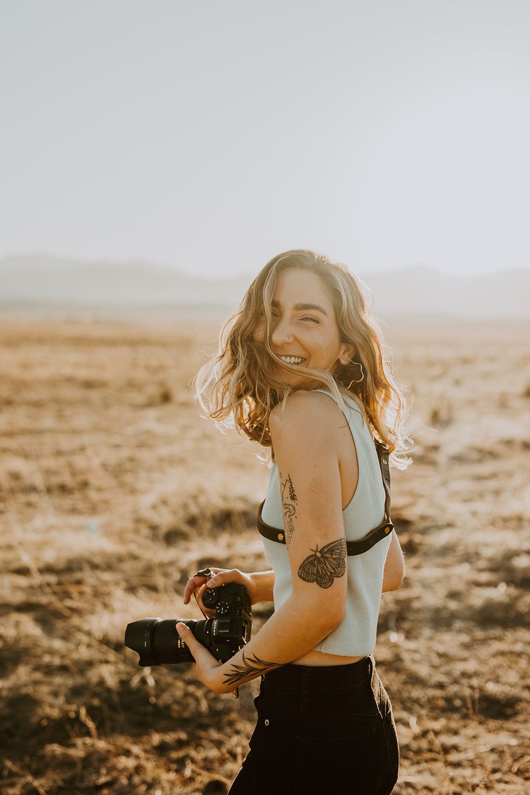 Colorado wedding and elopement photographer Dani Haims smiles while holding her beloved camera during a photoshoot
