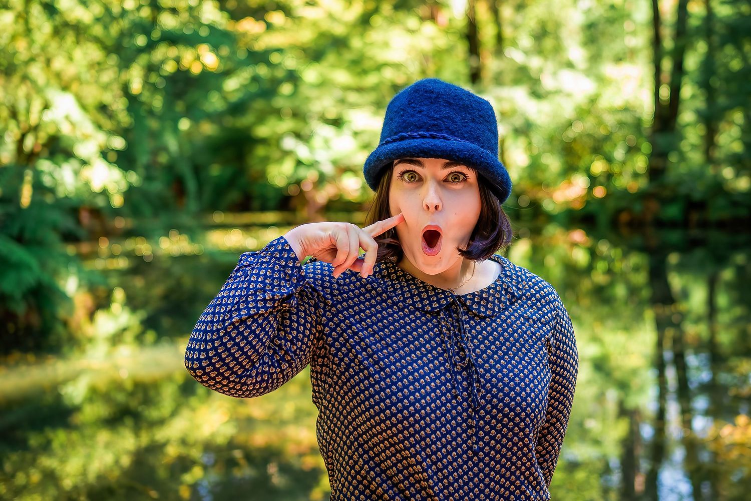 Female in a blue hat with a lake behind doing a Betty Boop impression.