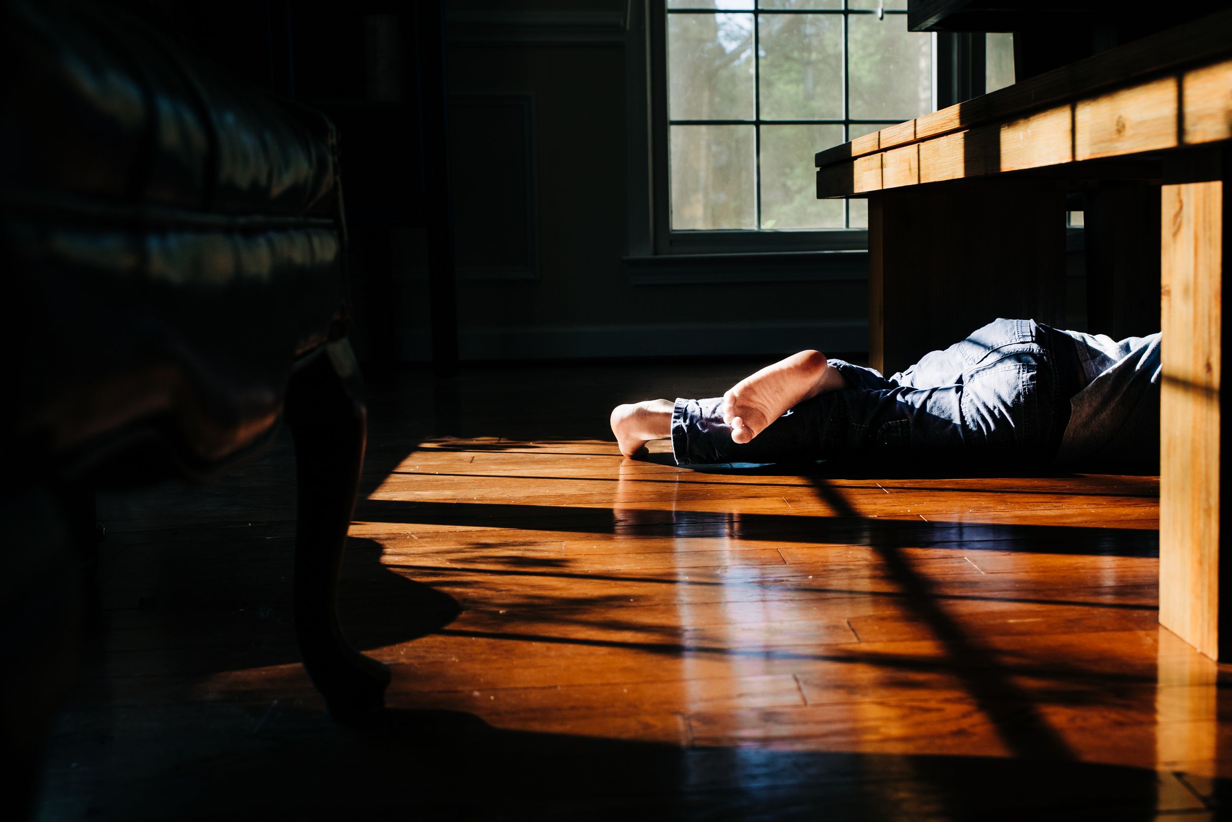 Young boys feet under a table with light hitting his legs
