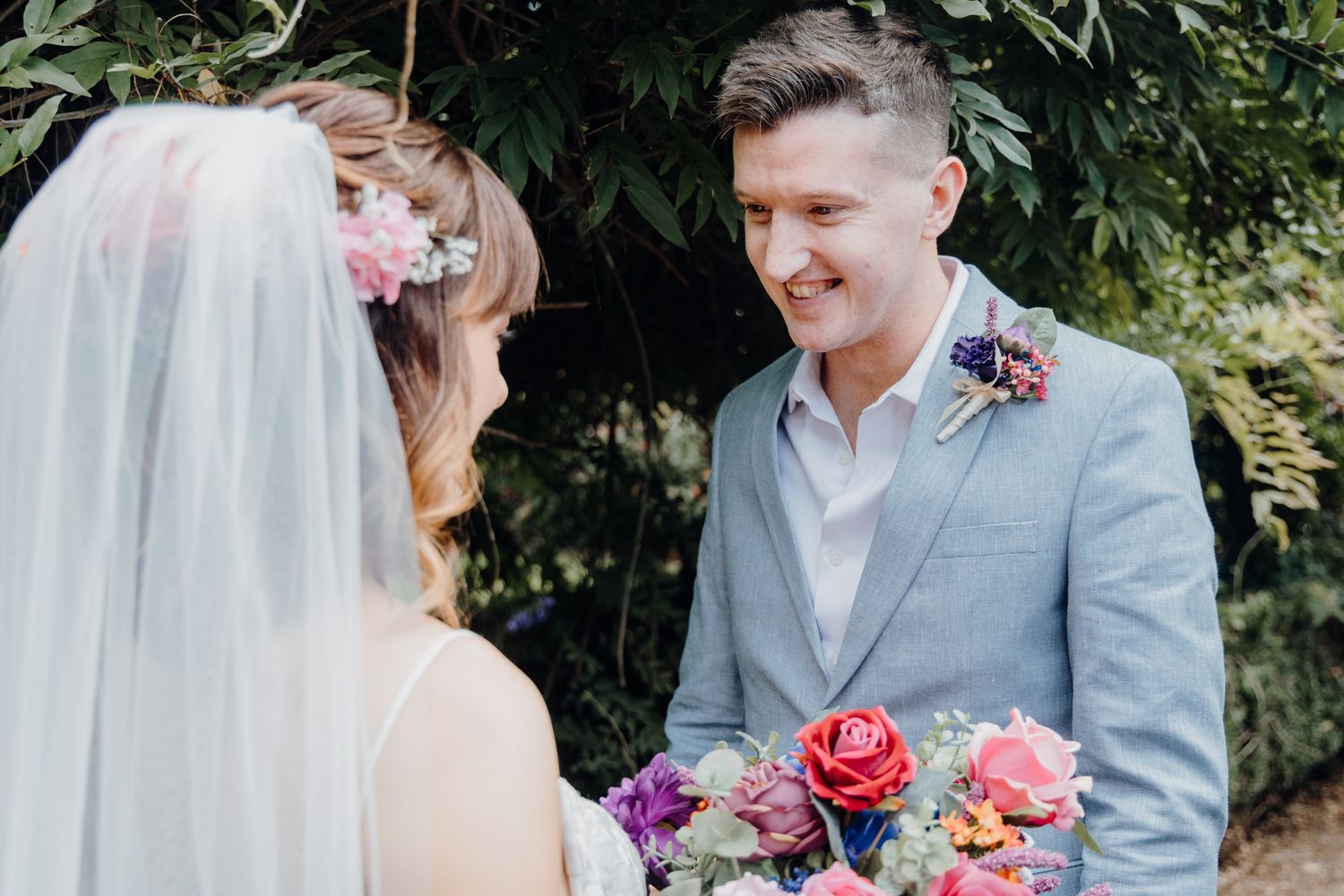 A couple shares an intimate moment in a garden setting with colorful flowers.