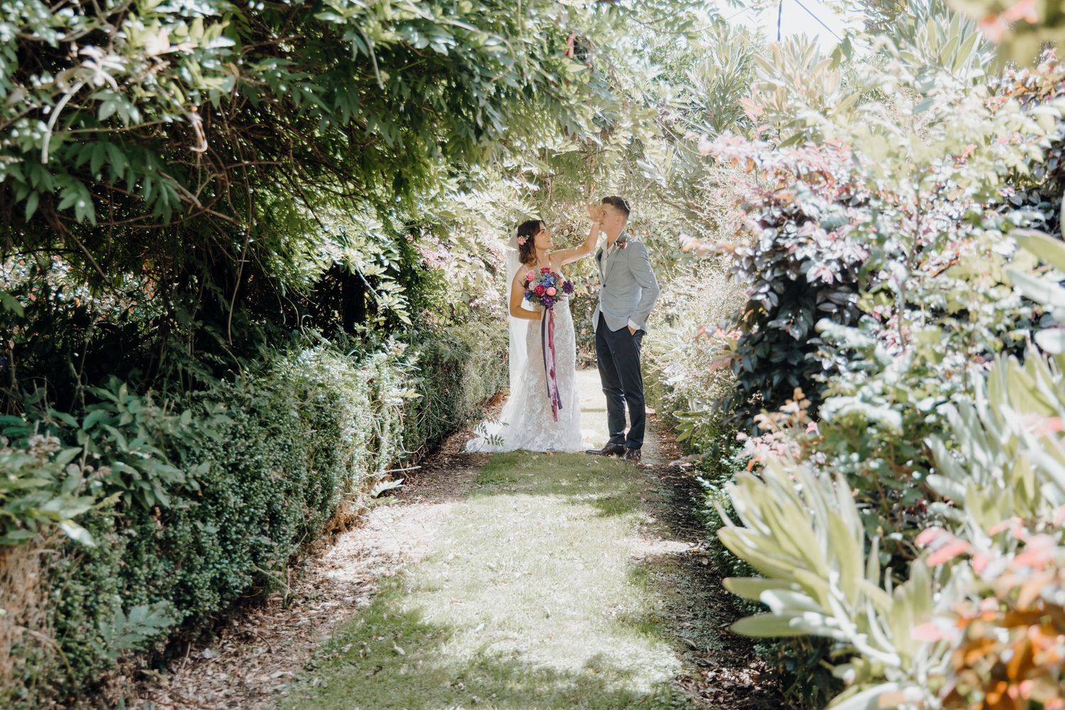 A romantic garden pathway framed with blooming flowers and greenery during a wedding ceremony.