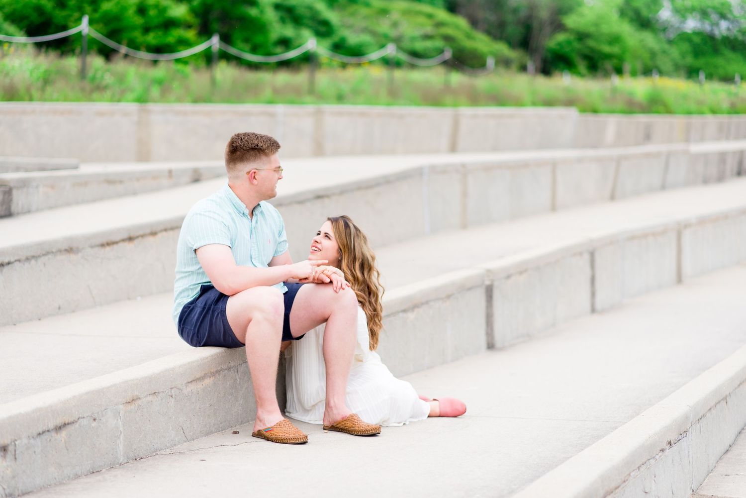 young couple sits on steps at Montrose Harbor overlooking lake Michigan