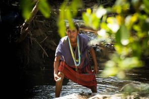 Enviromental portrait of Akha Tribe woman washing in the river