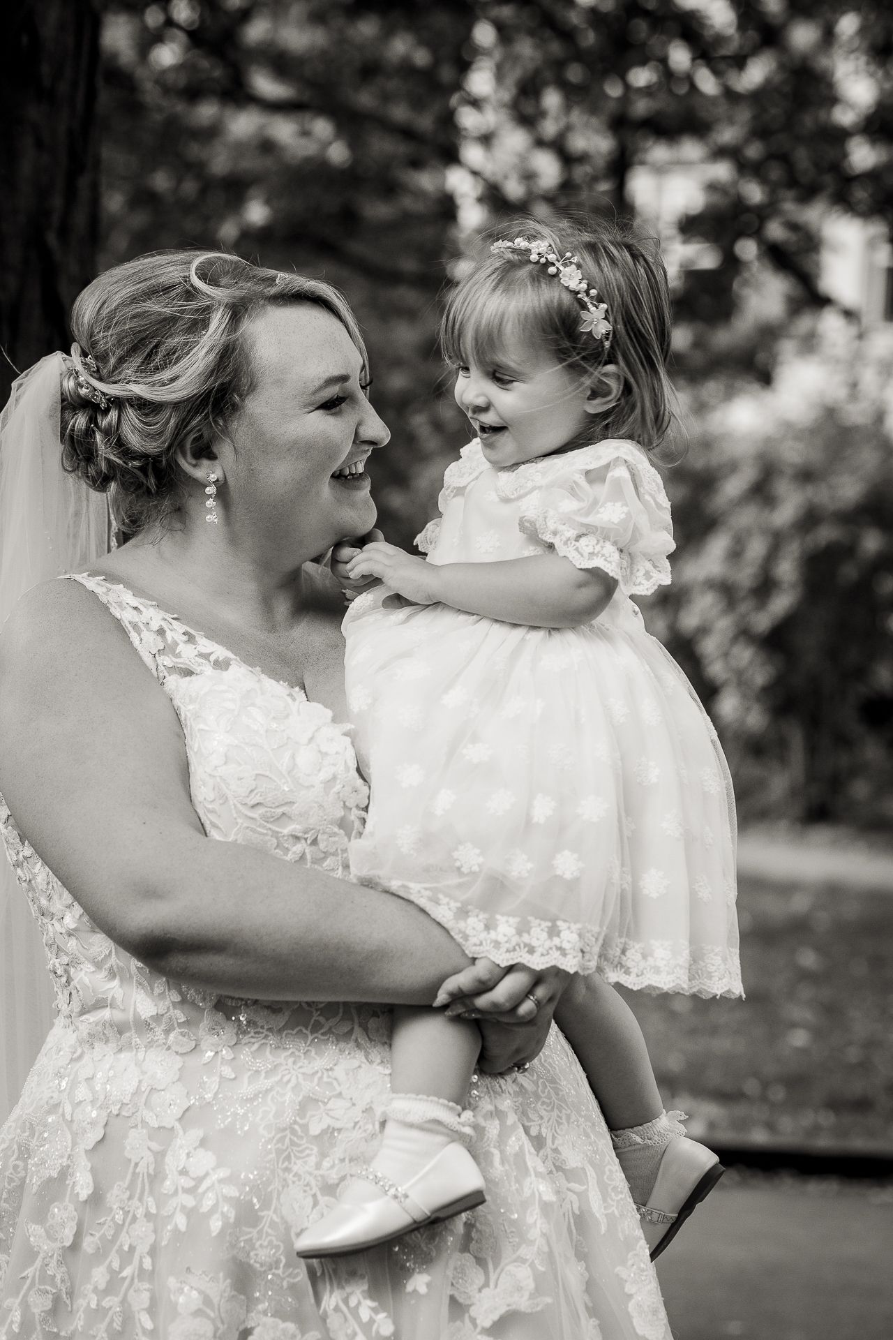 Black and white photography of bride and her flower girl smiling together in St Luke's Gardens.