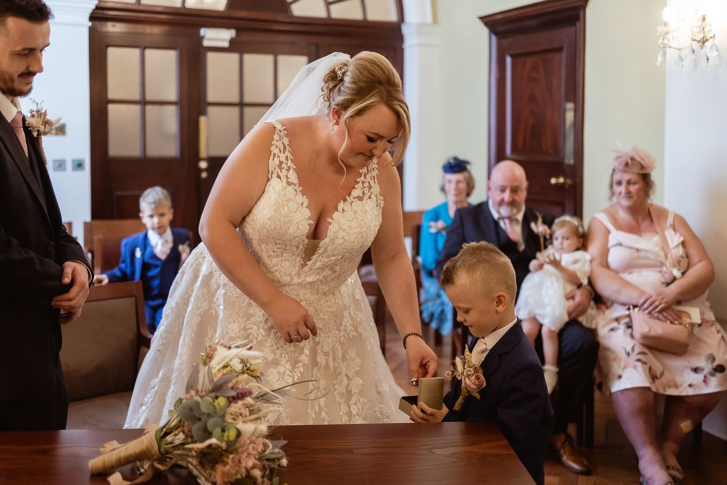 Bride taking the wedding band from her page boy in Rossetti Room wedding ceremony, London.