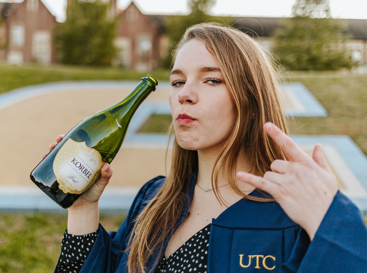 College graduate holding a bottle of champagne