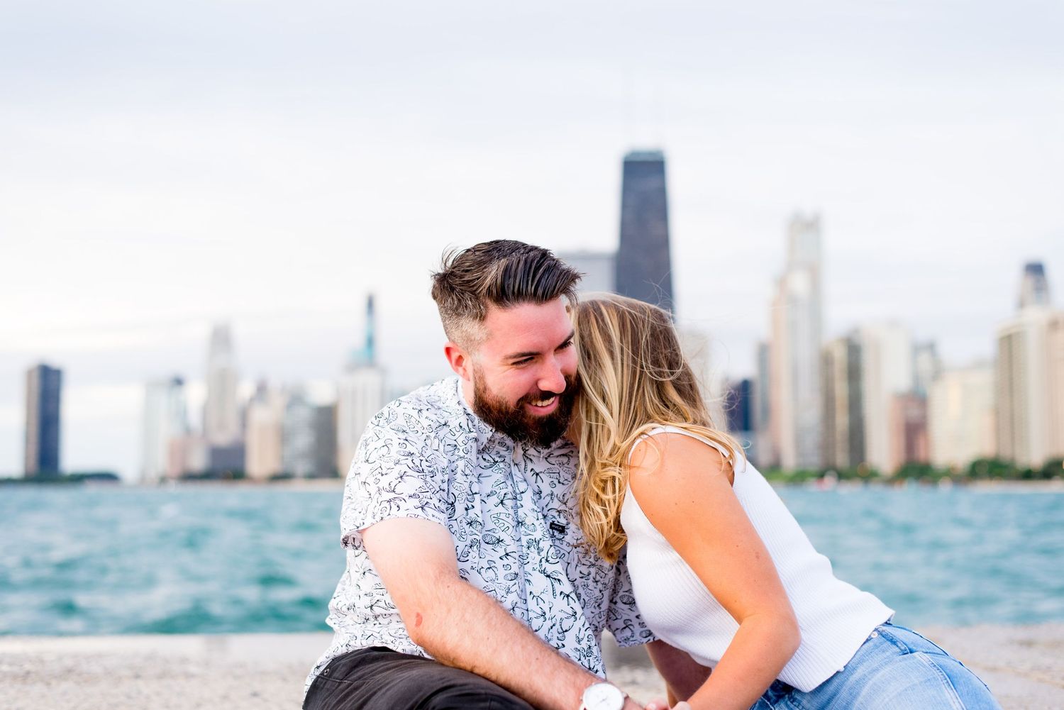 young blonde woman kisses neck of dark haired fiance at North Avenue Beach in the morning