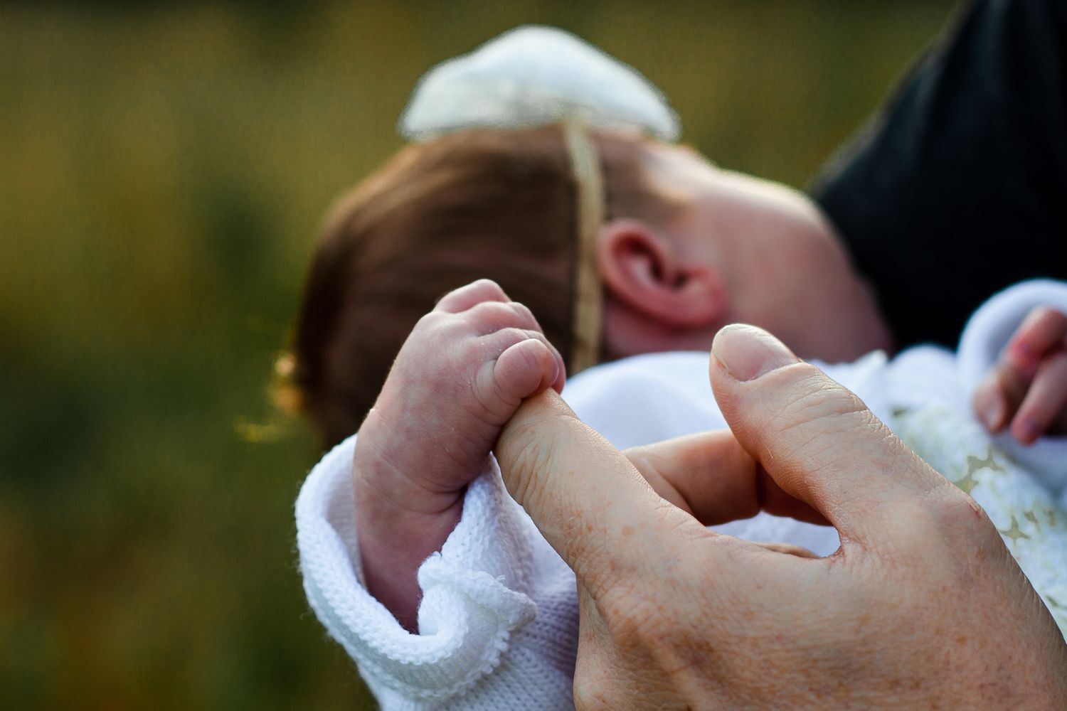 in a field in Havant, Hampshire, a newborn baby girl holds tight to her dad finger