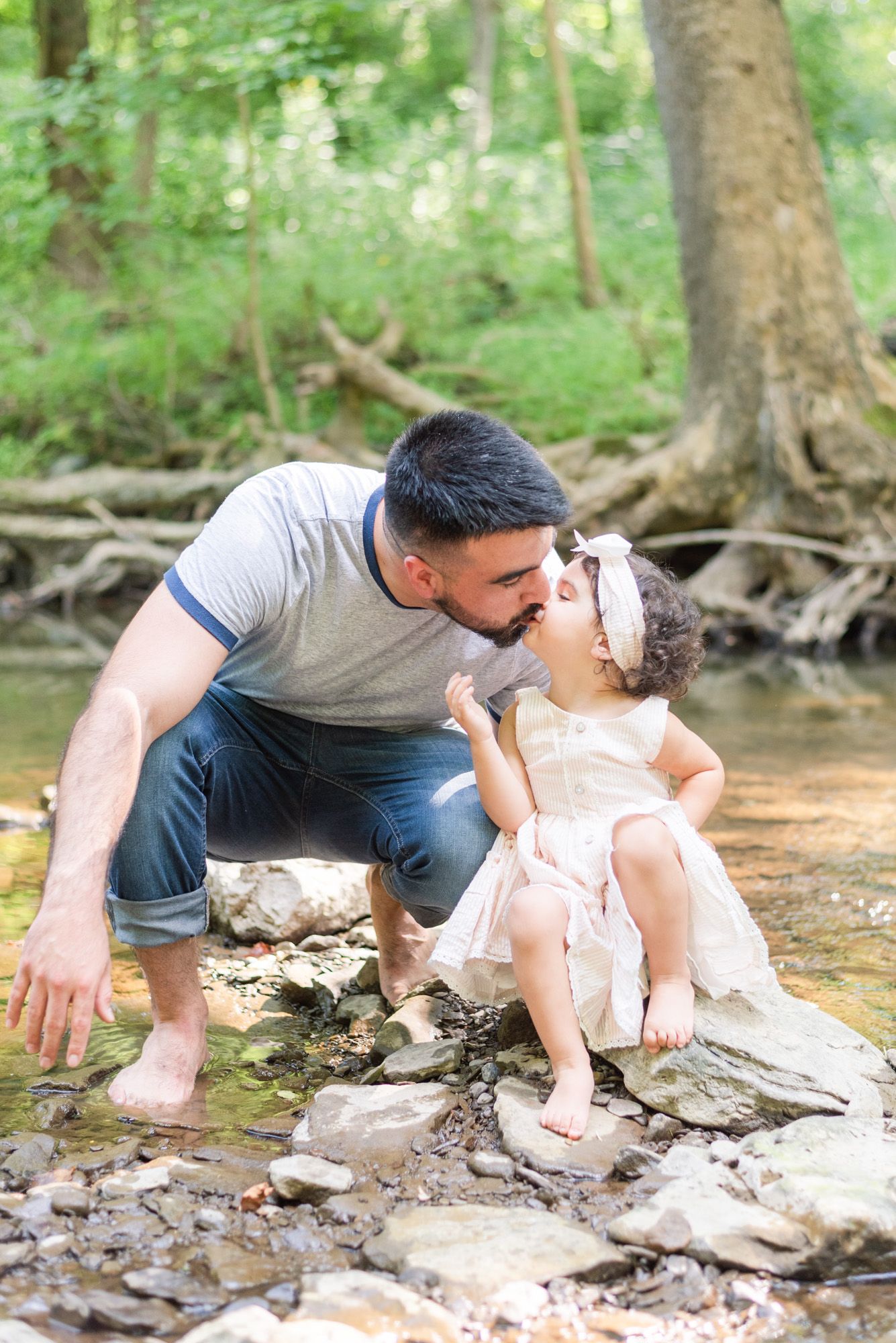 Dad and toddler kissing in creek in Pittsburgh, Pennsylvania