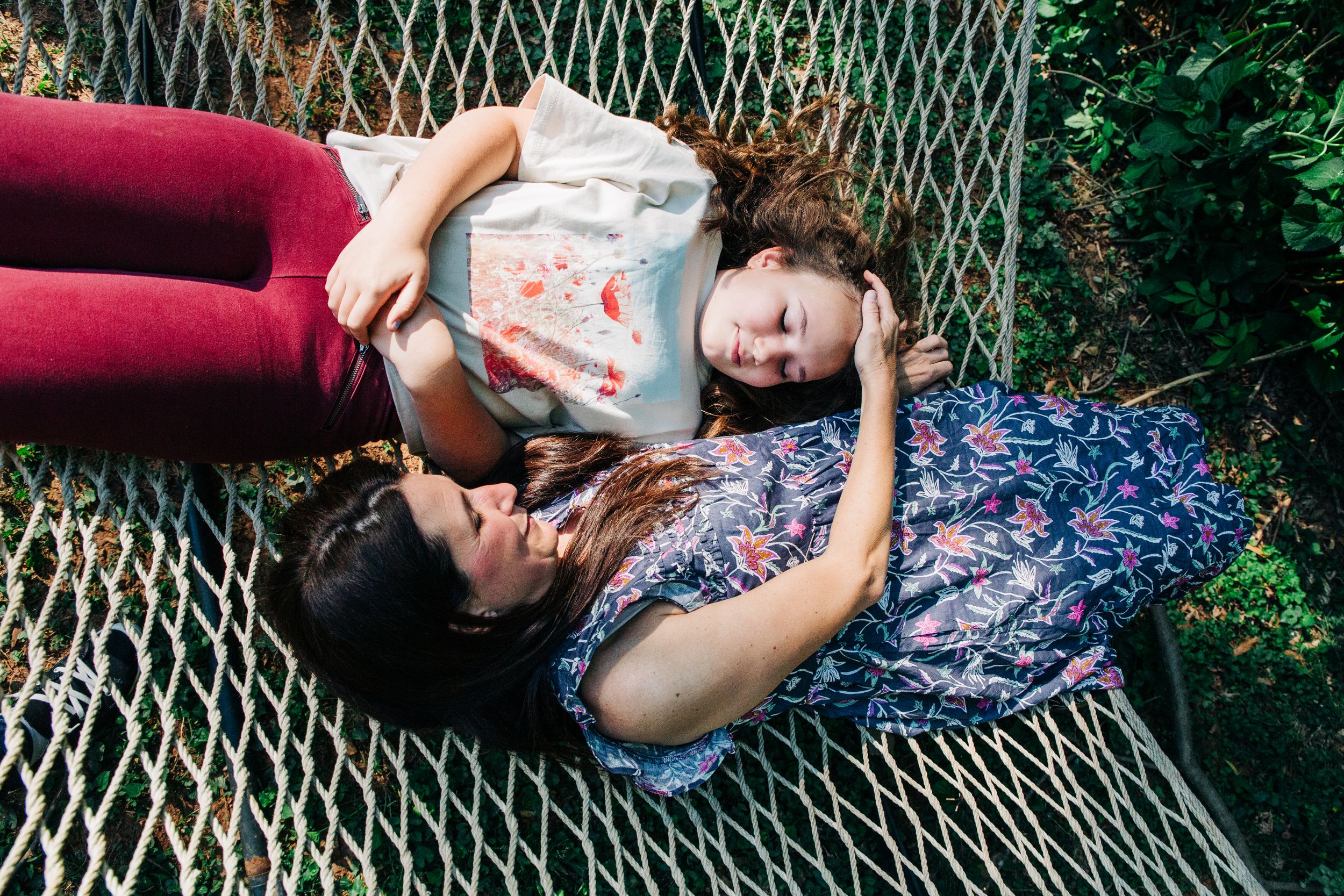 Mother and young teenage daughter lying together on a hammock in their Charlotte backyard