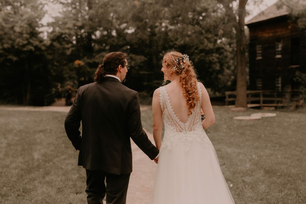 Back view of newlyweds walking together on grounds of rustic venue.