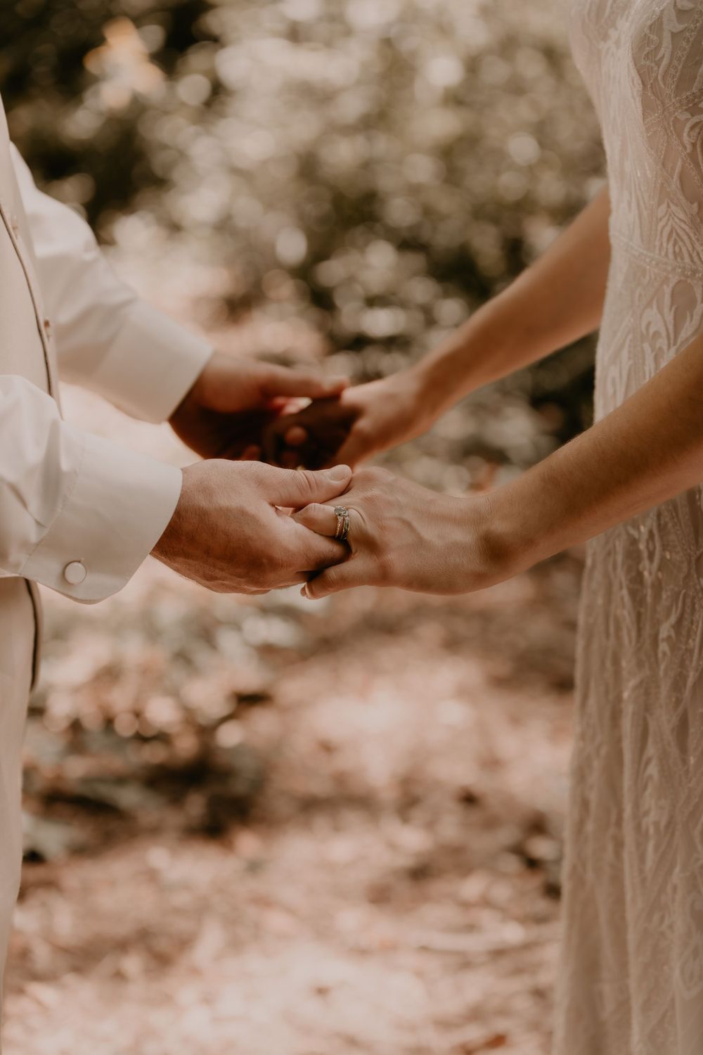 Close-up shot of hands exchanging rings during an outdoor wedding ceremony.