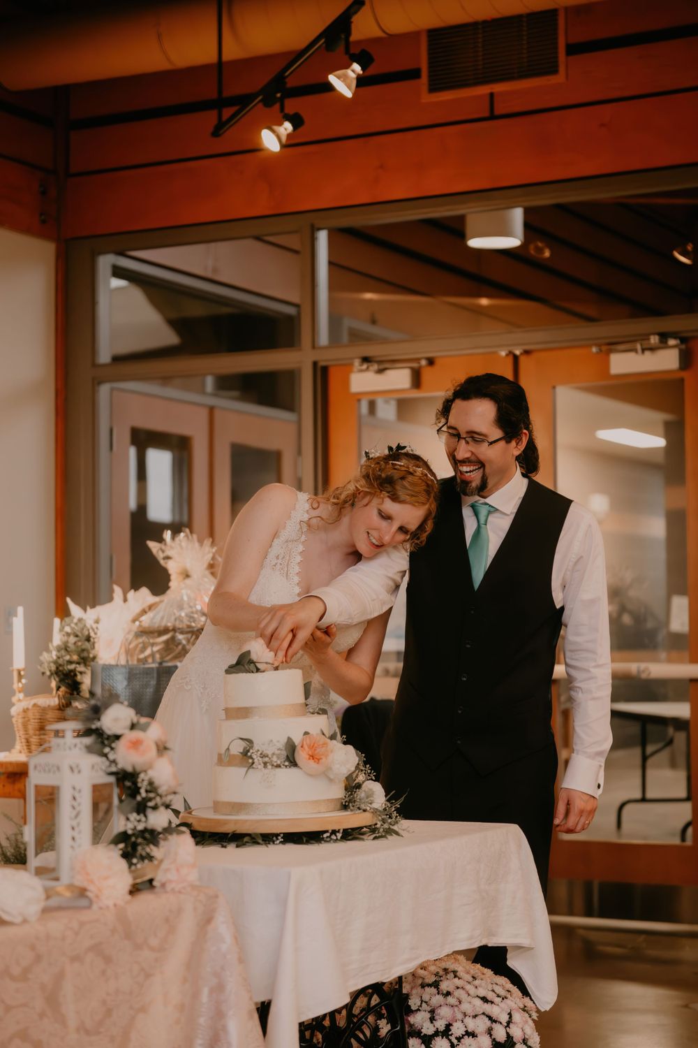 A couple sharing a sweet moment while cutting their elegant wedding cake at their reception.