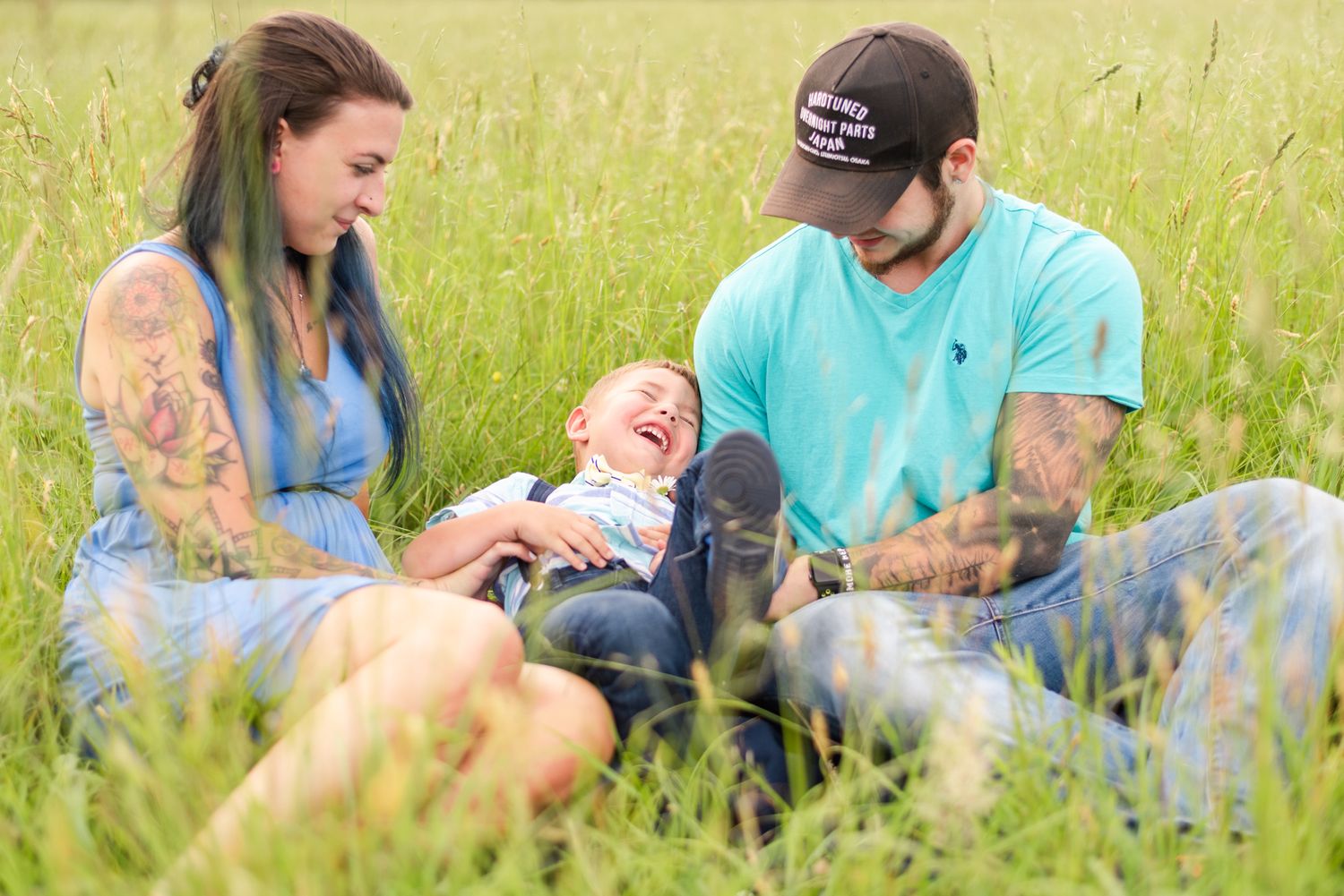 Little boy being tickled in field by mother and father in Clarion Pennsylvania
