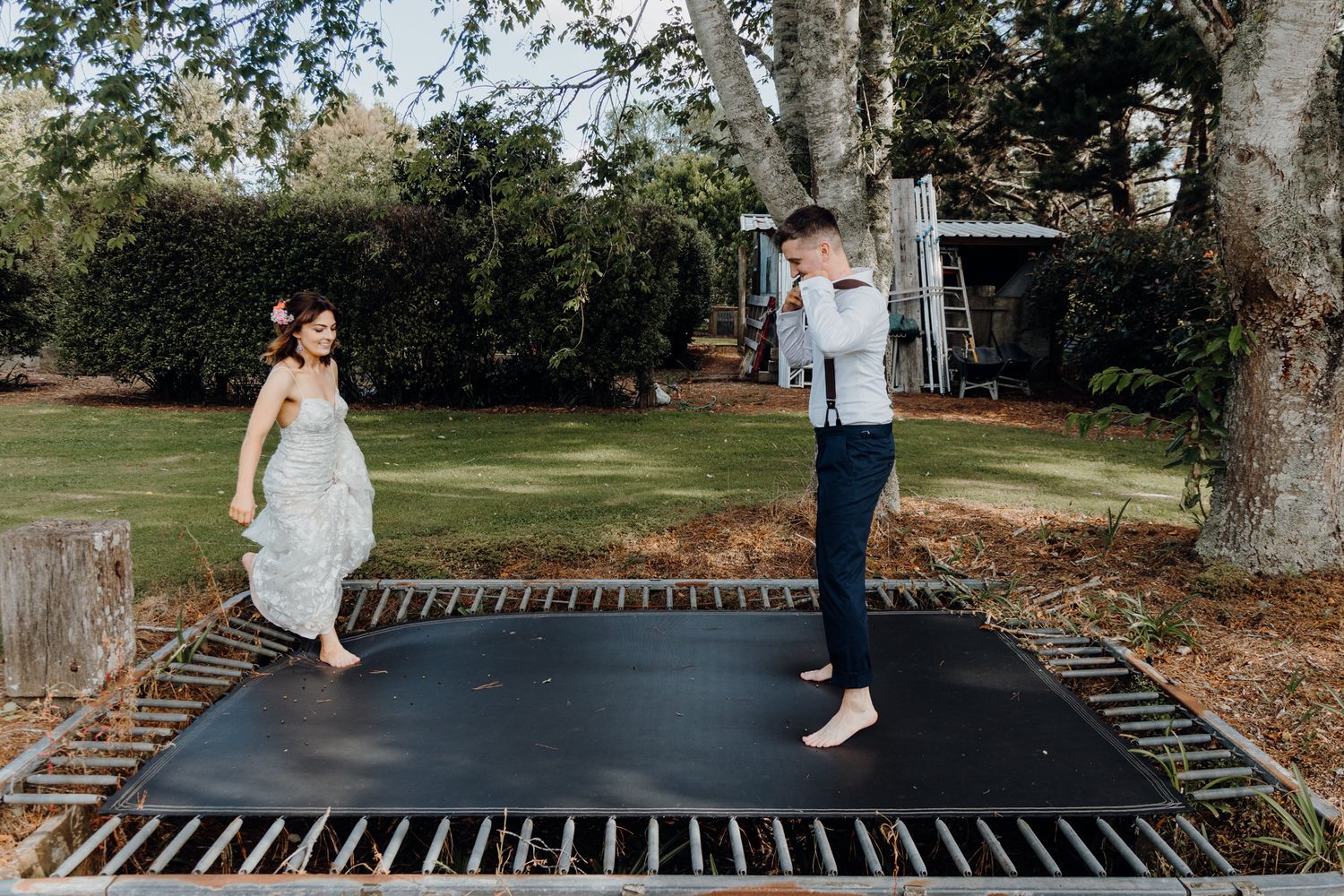 A playful wedding moment captured on a backyard trampoline.