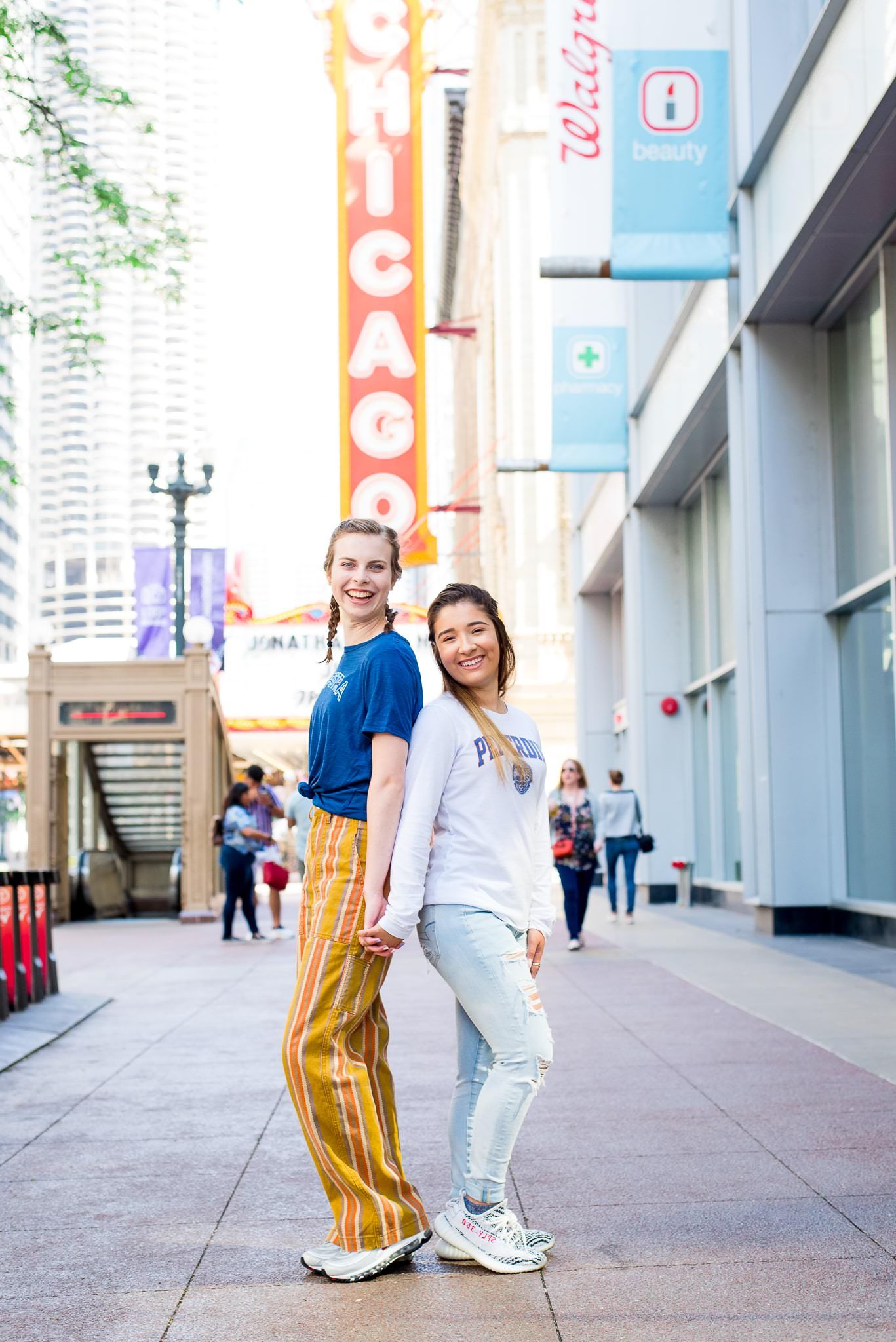 two senior girls in front of the Chicago Theater sign for Chicago senior pictures back to back