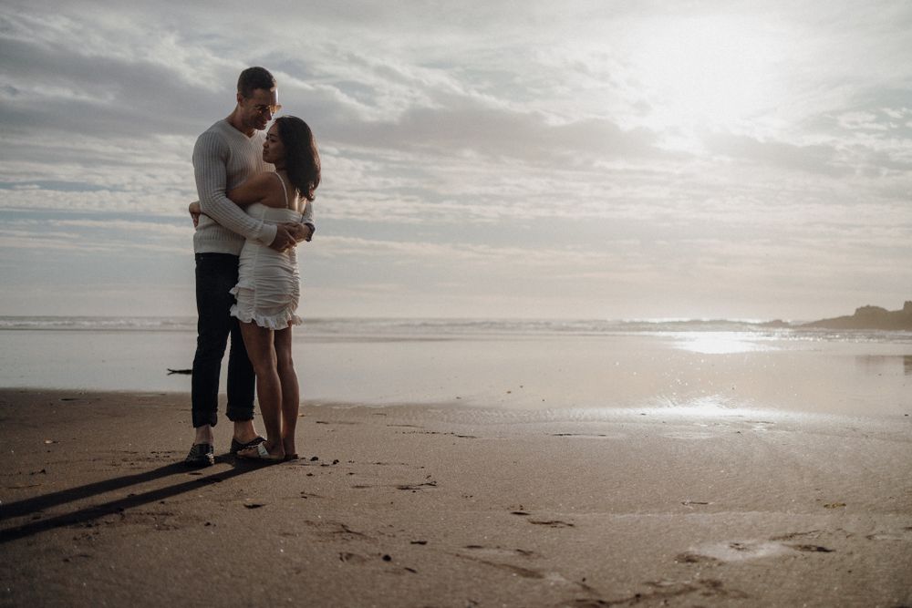 A tender embrace on a serene beach with gentle waves in the background.
