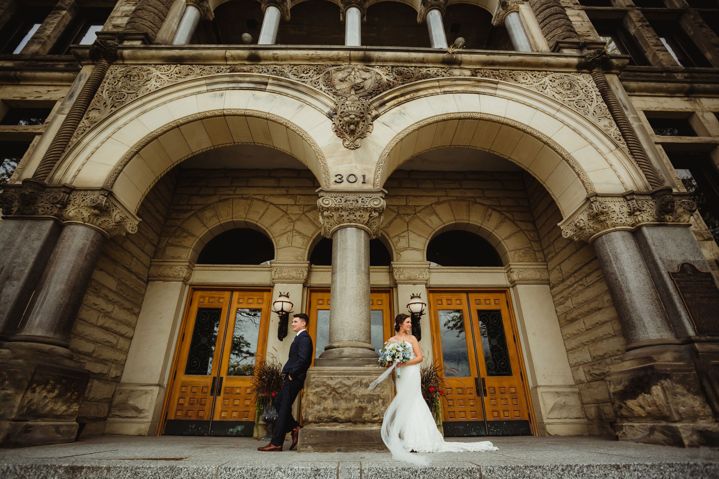 Bride and groom standing on either side of a pillar at the courthouse in Bay City.