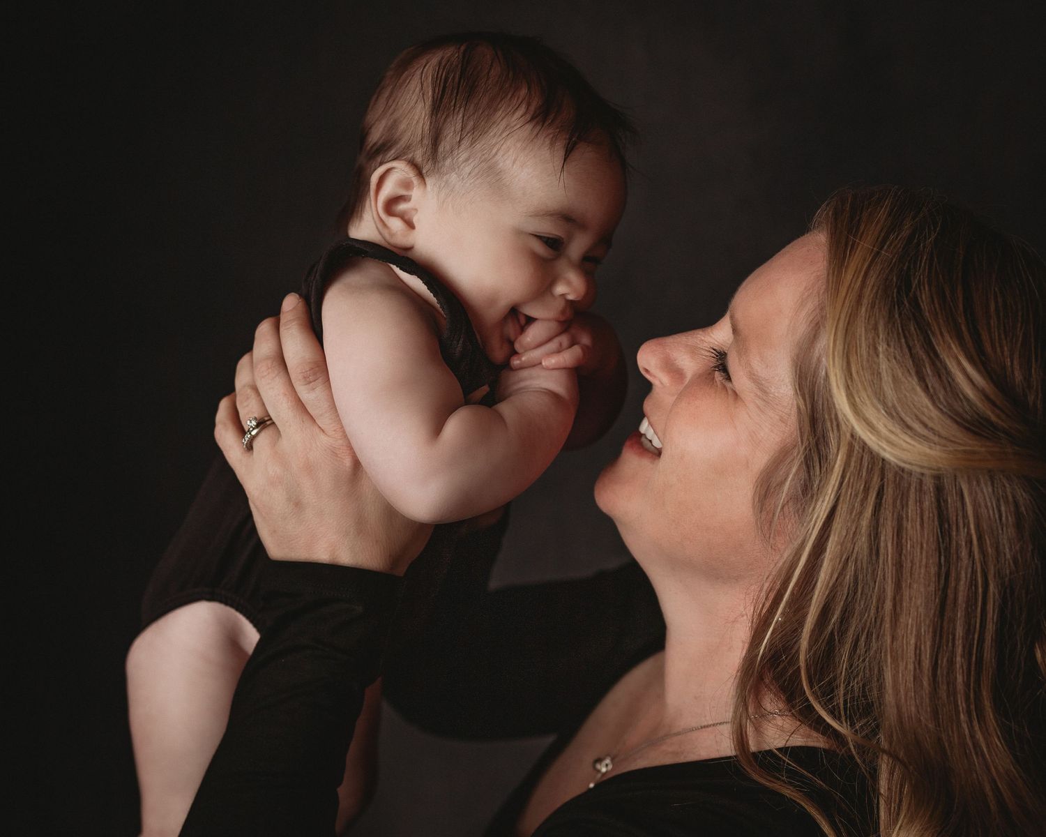 mother and daughter smiling matching black bodysuit happy baby