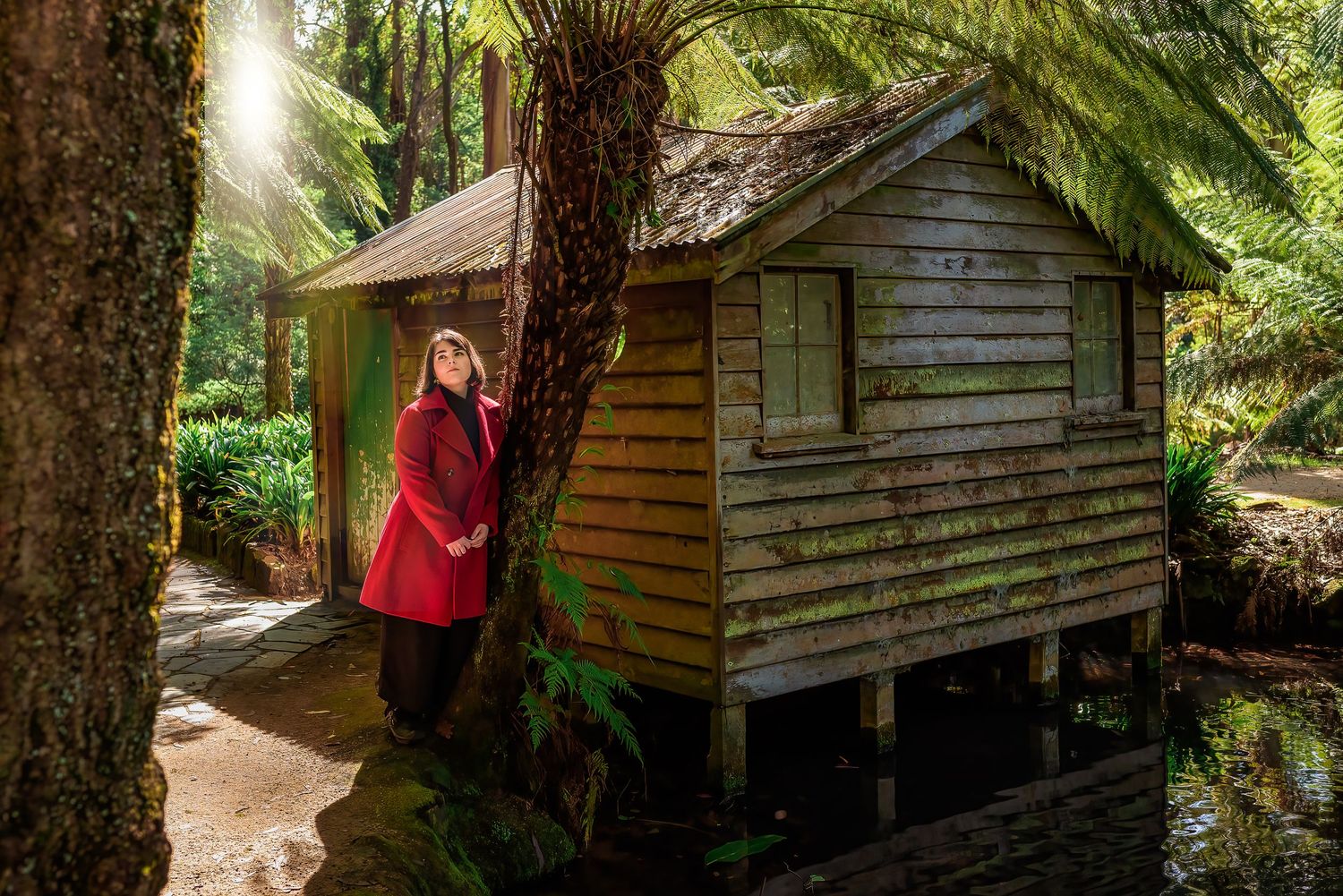 Female in red coat at boathouse in Alfred Nicholas Gardens, Melbourne.