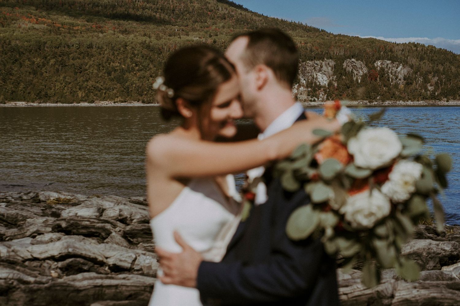 la mariée prenant le marié dans ses bras avec son bouquet coloré sur la plage de cap-aux-oies dans charlevoix, quebec