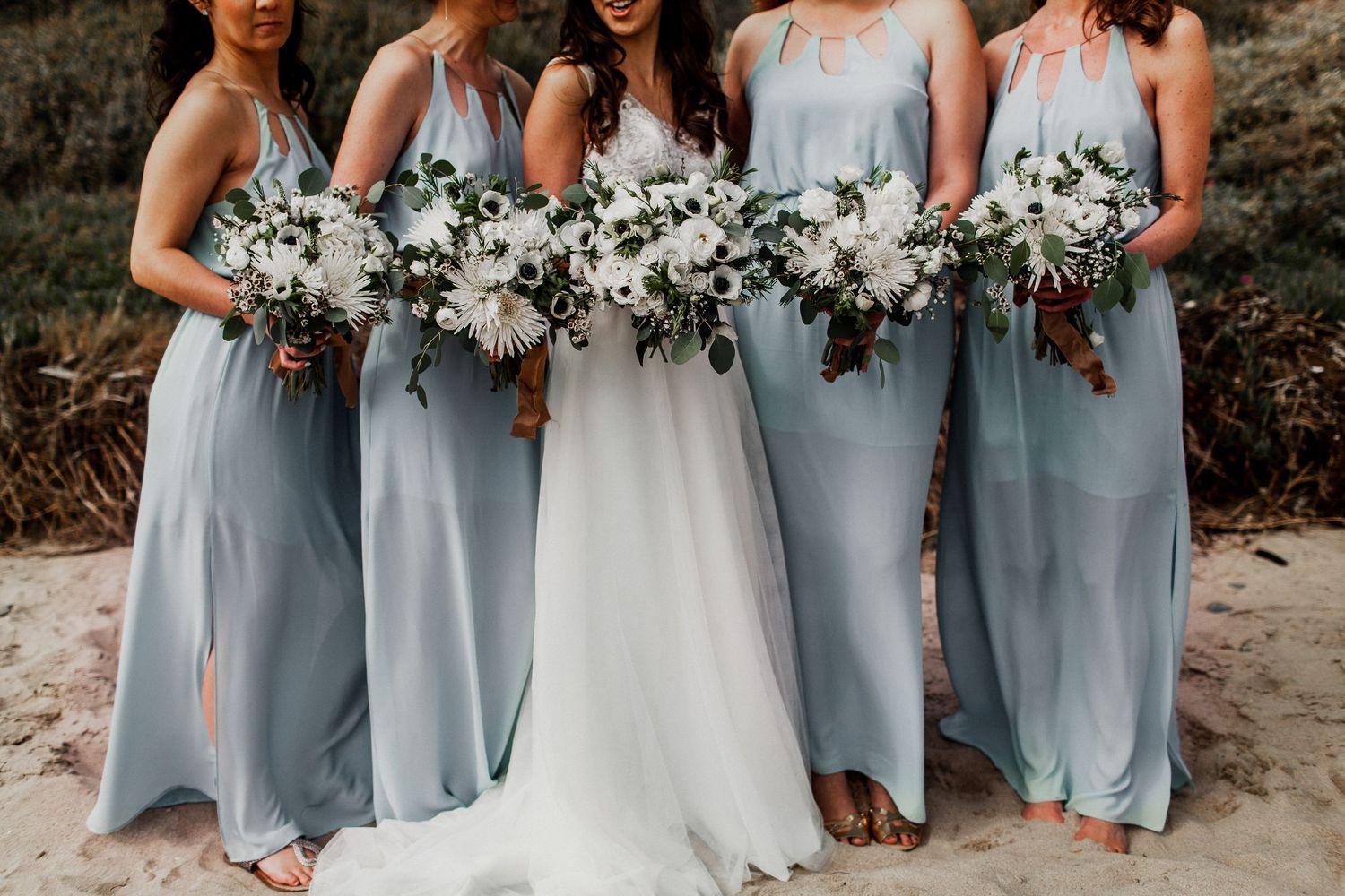 bridesmaids with blue dress and bridal party with flowers